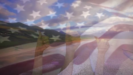 Animation-of-flag-of-america-waving-over-three-hands-with-thumbs-up-with-sunny-beach-and-sea
