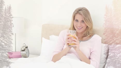 Animation-of-smiling-woman-sitting-in-bed-drinking,-over-misty-mountain-landscape