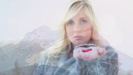 Animation-of-woman-holding-red-pills-on-outstretched-hand,-over-misty-mountain-landscape