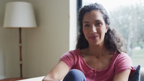 Portrait-of-happy-mixed-race-woman-,sitting-living-in-room