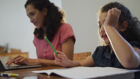Glückliche-Gemischtrassige-Mutter-Und-Tochter,-Die-Zu-Hause-Hausaufgaben-Machen-Und-Am-Laptop-Arbeiten