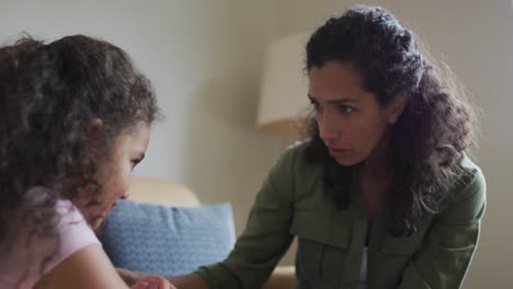 Mixed-race-mother-advising-her-daughter-on-the-sofa-in-living-room