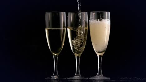 Animation-of-champagne-pouring-into-three-glasses-on-black-background