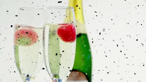Animation-of-confetti-falling-and-strawberries-dropping-into-in-glasses-of-champagne,-on-white