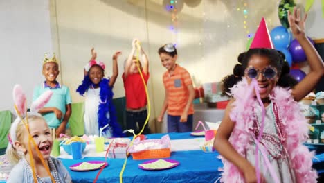 Animation-of-red-shapes-spinning-over-children-having-fun-at-party