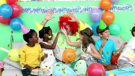 Animation-of-gold-confetti-falling-over-diverse-happy-children-and-clown-having-fun-at-party