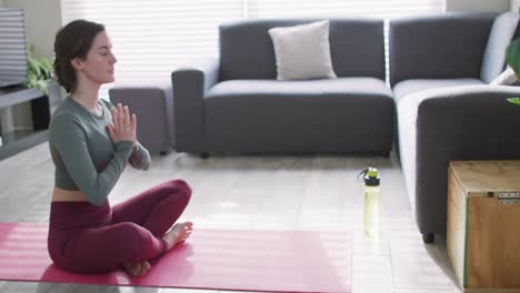 Mujer-Caucásica-Manteniéndose-En-Forma-Y-Meditando-Sobre-Una-Estera-De-Yoga.