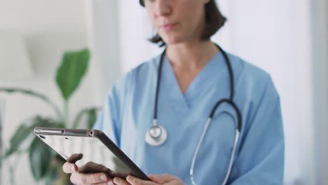 Caucasian-female-doctor-at-home-using-tablet