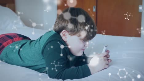 Animation-Von-Molekülen-über-Einem-Jungen,-Der-Sein-Smartphone-Benutzt