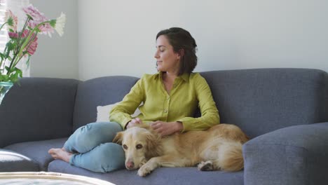 Caucasian-woman-smiling-and-sitting-on-couch-with-dog