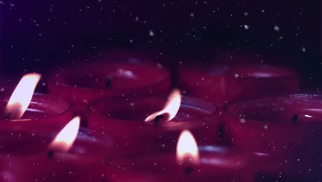 Animation-of-snow-falling-over-lit-red-candles