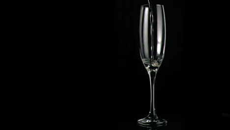 Animation-of-red-specks-floating-over-glass-of-champagne-on-black-background