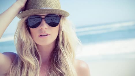 Portrait-of-caucasian-woman-wearing-sunglasses-and-hat-on-a-beach
