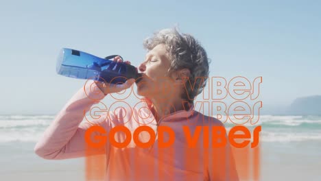 Animation-of-text-good-vibes,-in-orange,-over-woman-drinking-water-on-beach