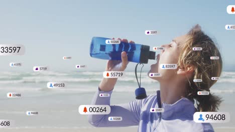 Animation-Von-Social-Media-Benachrichtigungen-über-Eine-Frau,-Die-Am-Strand-Wasser-Trinkt