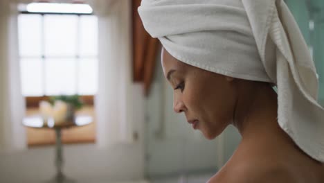 Portrait-of-mixed-race-woman-wearing-towel-on-head-looking-at-camera-and-smiling