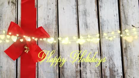 Animation-of-text,-happy-holidays,-in-yellow-with-string-lights-and-red-christmas-bow-decoration