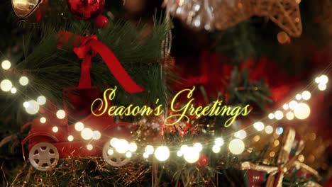 Animation-of-text,-season's-greetings,-in-yellow,-over-string-lights-and-decorated-christmas-tree