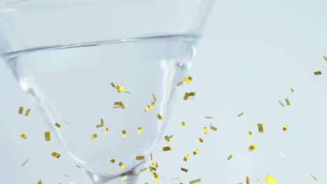 Animation-of-gold-confetti-falling-over-into-clear-drink-in-glass,-on-white-background