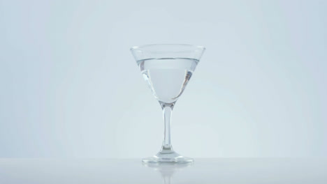 Animation-of-red-specks-moving-over-cocktail-glass-with-olives-on-white-background