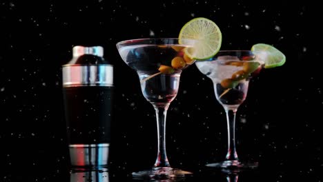Animation-of-specks-moving-over-cocktail-glasses-with-olives-and-ice-on-black-background