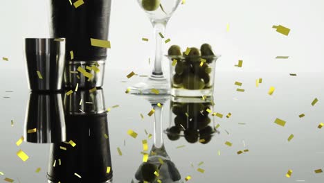Animation-of-confetti-falling-over-cocktail-glass-with-olives-on-white-background