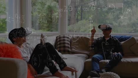 Animation-of-mathematical-drawings-and-equations-over-father-and-son-wearing-vr-headsets