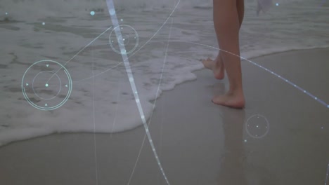 Network-of-connections-against-low-section-of-a-woman-walking-at-the-beach