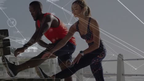 Network-of-connections-against-mixed-race-couple-performing-stretching-exercise-on-the-promenade