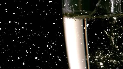 Animation-of-falling-confetti-over-glass-of-champagne