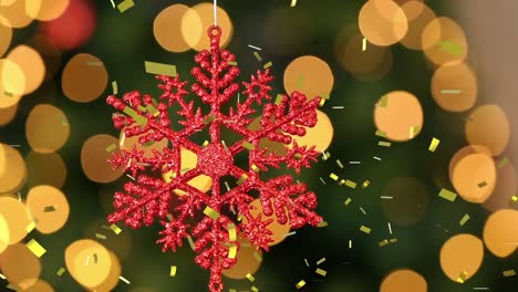 Animation-of-gold-confetti-falling-over-red-snowflake-christmas-tree-decoration,-with-bokeh-lights