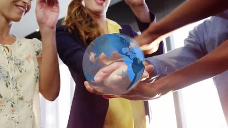 Animation-of-globe-rotating-over-happy-diverse-colleagues-stacking-hands-at-casual-office-meeting