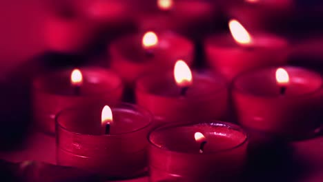 Animation-of-burning-document-over-lit-red-candles-on-black-background