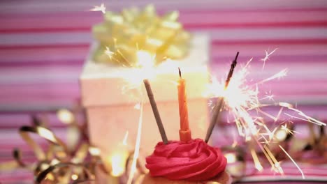 Animation-of-yellow-and-white-zigzag-lines-over-sparklers-and-candle-on-cupcake
