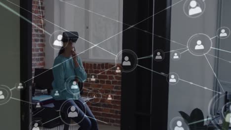Animation-of-network-of-connections-over-businesswoman-using-vr-headset-in-office