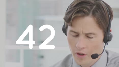 Changing-numbers-against-caucasian-male-customer-care-executive-talking-on-phone-headset-at-office