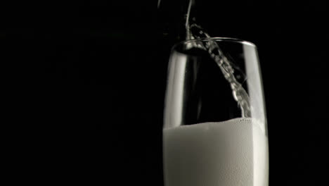 Graues-Papier-Brennt-Vor-Champagner,-Der-Vor-Schwarzem-Hintergrund-In-Ein-Glas-Gegossen-Wird