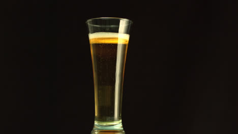 Papier-Brennt-Und-Konfetti-Fällt-über-Bier,-Das-Vor-Schwarzem-Hintergrund-In-Ein-Glas-Strömt