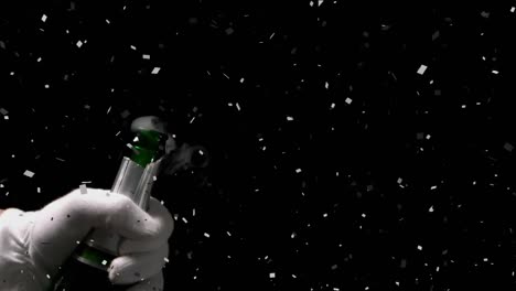 Grey-paper-burning-and-confetti-falling-over-mid-section-of-person-opening-a-champagne-bottle
