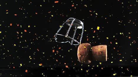 Confetti-falling-over-champagne-cork-and-opener-falling-against-black-background