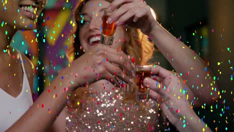 Colorful-confetti-falling-over-group-of-female-friends-toasting-their-drinks-at-a-bar