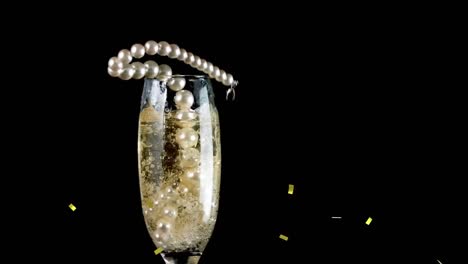 Animation-Von-Konfetti-über-Einer-Halskette,-Die-In-Ein-Glas-Mit-Champagner-Auf-Schwarzem-Hintergrund-Fällt