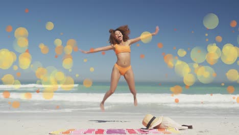 Animation-of-african-american-woman-jumping-for-joy-at-beach-over-yellow-spots