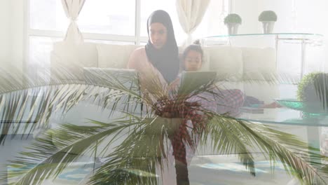 Animation-of-asian-mother-in-hijab-sitting-with-daughter-over-landscape