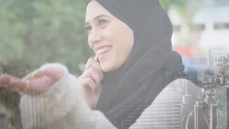 Animation-of-asian-woman-in-hijab-using-smartphone-over-cityscape