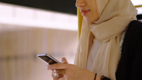 Animation-Einer-Asiatischen-Frau-Im-Hijab-Mit-Smartphone-über-Dem-Stadtbild