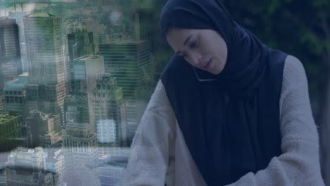 Animation-of-ssian-woman-in-hijab-using-smartphone-over-cityscape