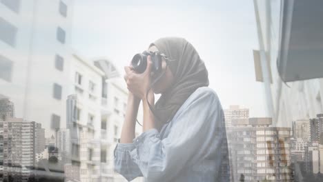 Animation-of-asian-woman-in-hijab-using-camera-over-cityscape