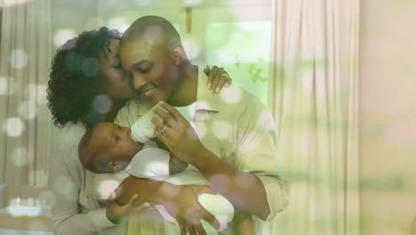 Animation-of-happy-african-american-parents-feeding-baby-at-home-over-white-spots