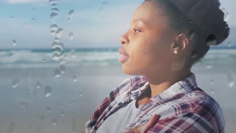 Animation-of-african-american-woman-relaxing-at-beach-over-droplets